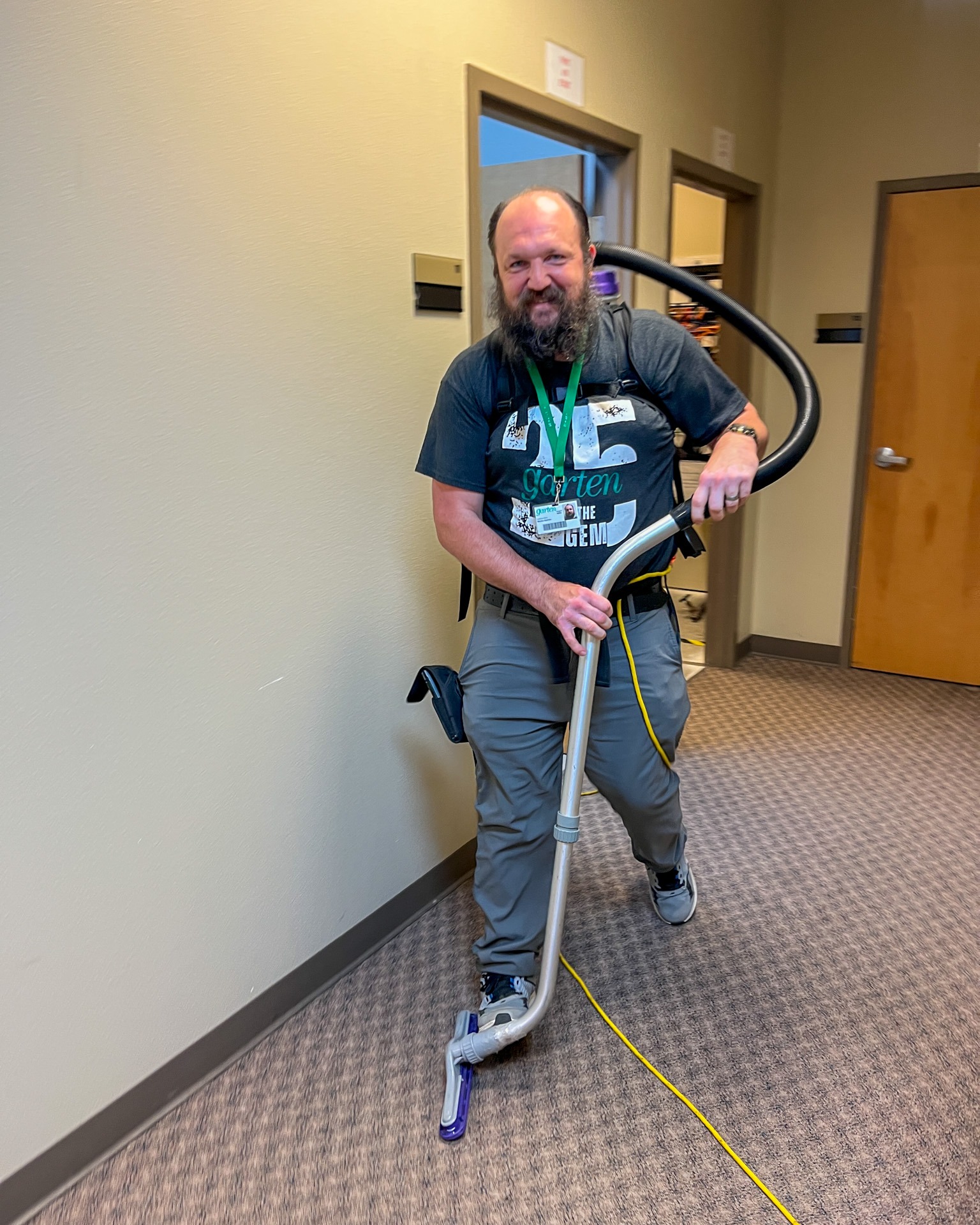Professional cleaner vacuuming down a hallway.
