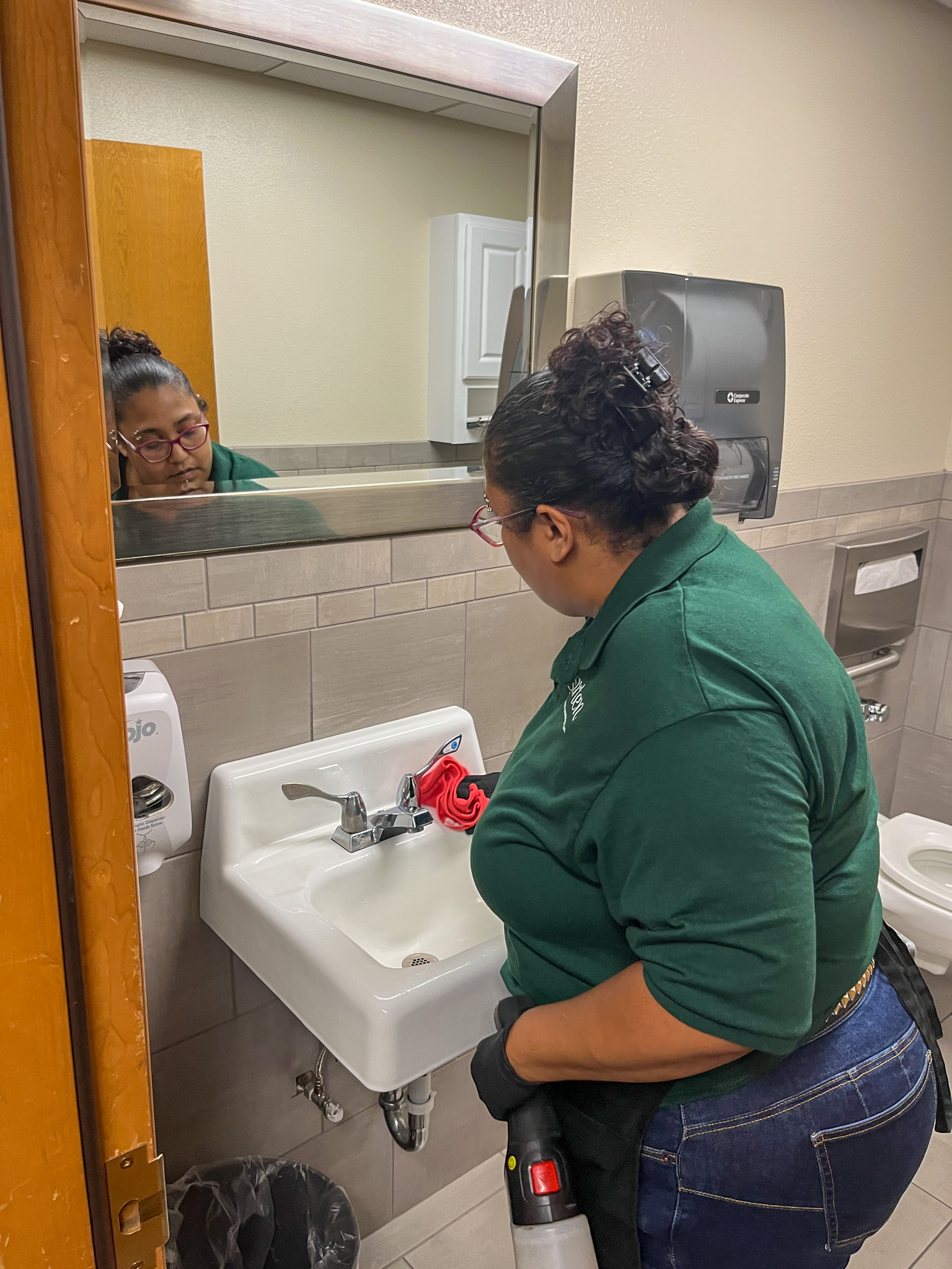 Professional janitorial staff sanitizing office surfaces with cleaning equipment.