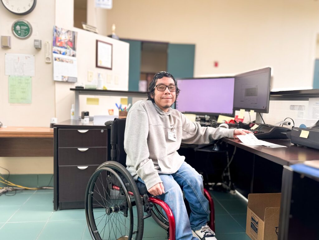 Juan sits at his desk as the receptionist for Garten in Salem Oregon. 